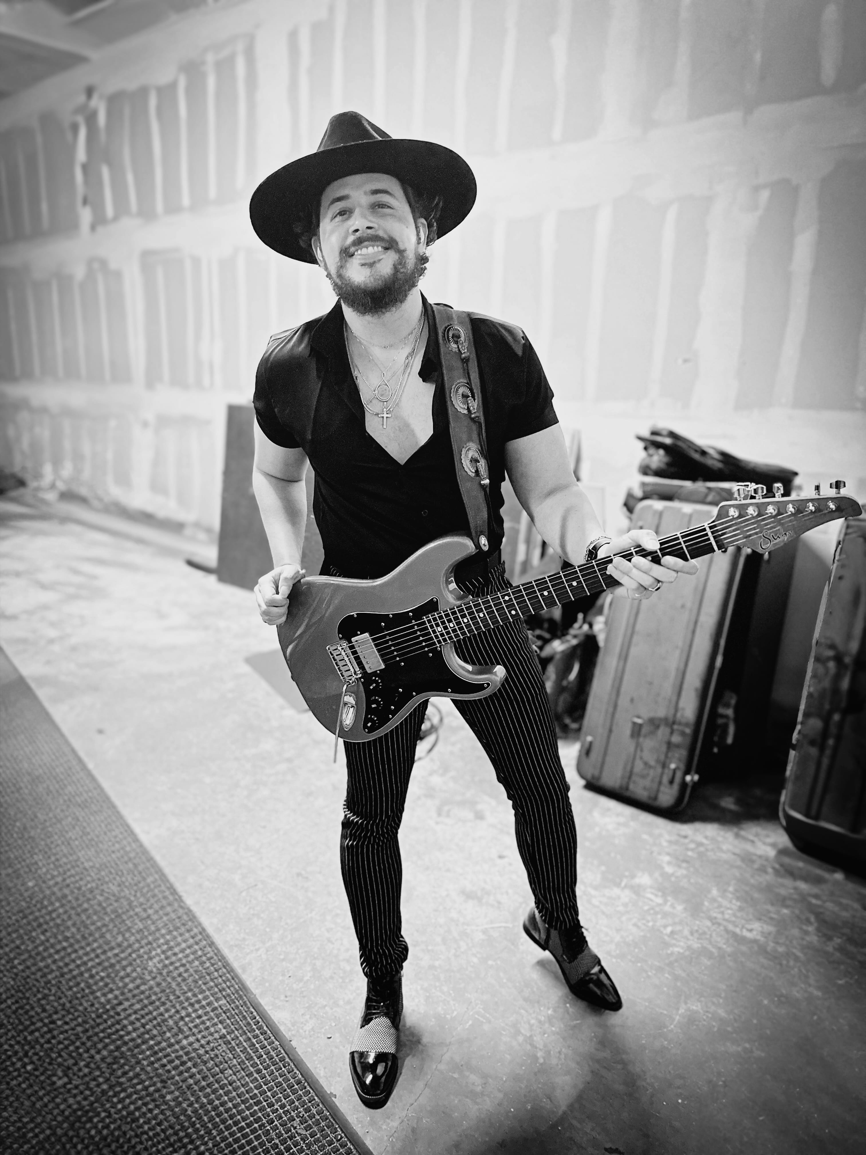 Will Plus smiling with his electric guitar in a black-and-white artist portrait